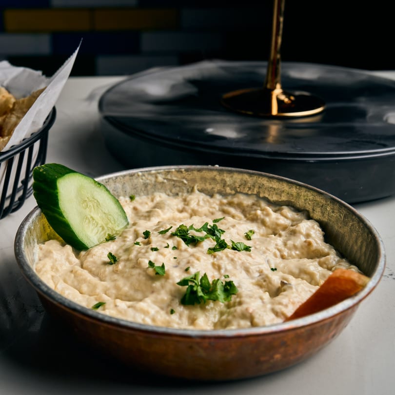 Adana Restaurant's creamy baba ghanoush, garnished with parsley and a cucumber slice, served with pita.
